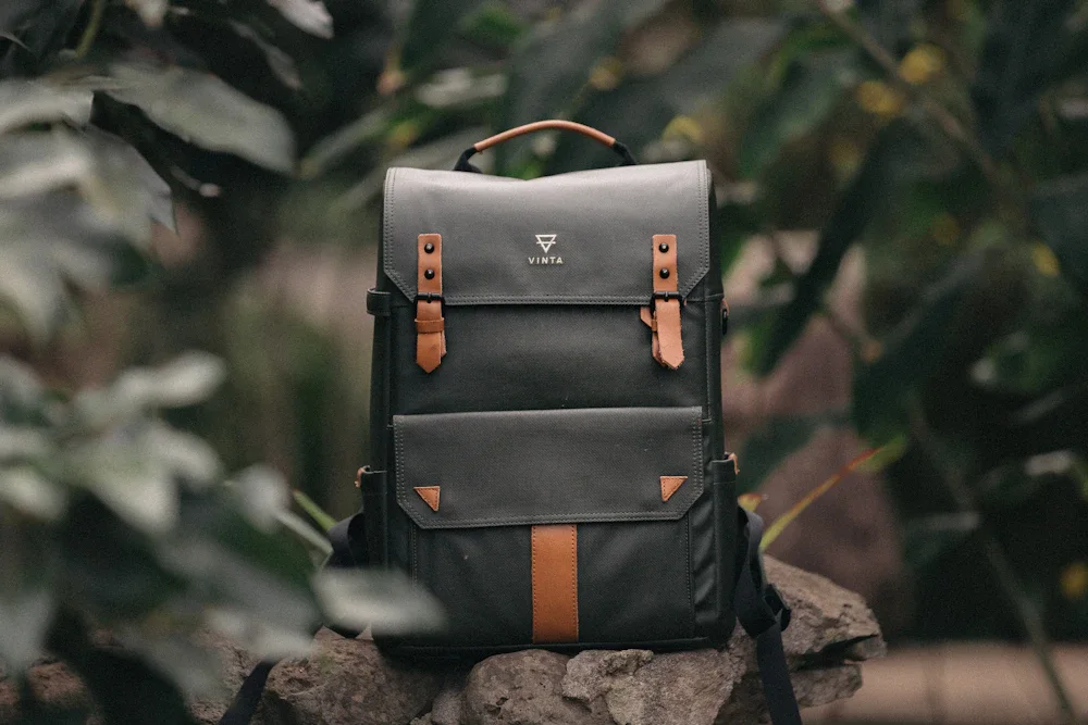 Leather bags in forest green, burgundy, and slate blue displayed on a clean white shelf