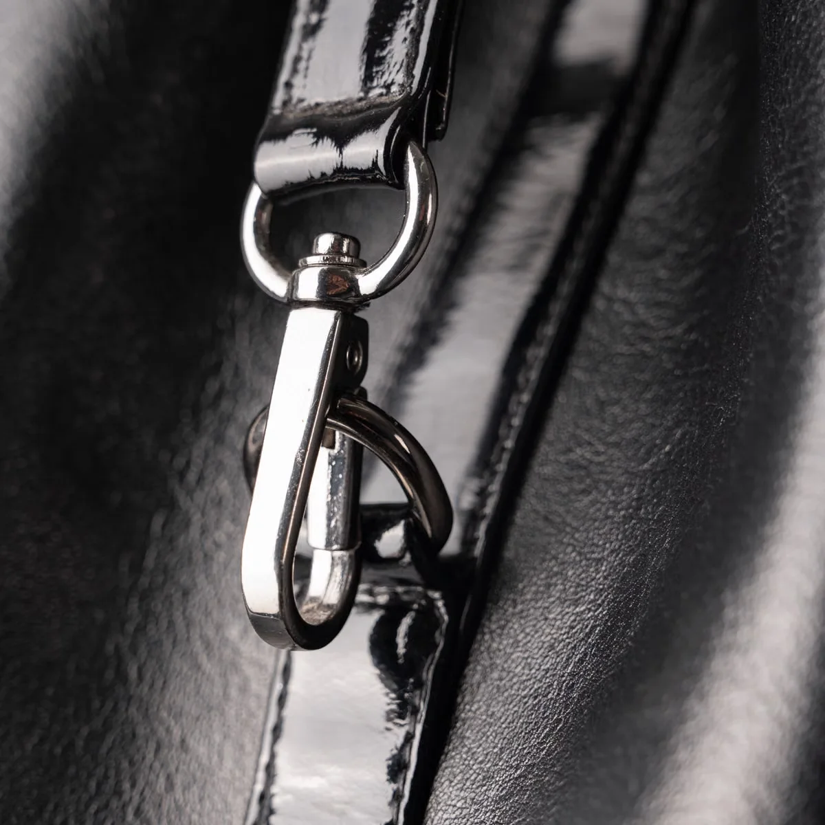 Close-up of a leather bag adjustable strap with silver swivel clasp hardware — strap attachment method, hardware type and finish are among the most frequently misspecified elements in leather bag tech packs